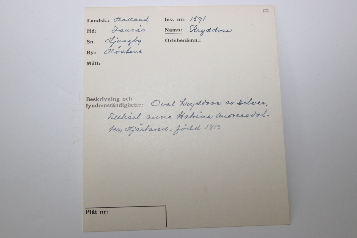 Oval ask i silver. Namnen "P Andersson" och "AC Andersdoter" är inristade på lockets ovansida, omgivna av en dekorativ bård med triagulära mönster. Asken är stämplad på botten på insdian av asken med kattfot, i4 (år 1839) och två svårtydda stämplar.