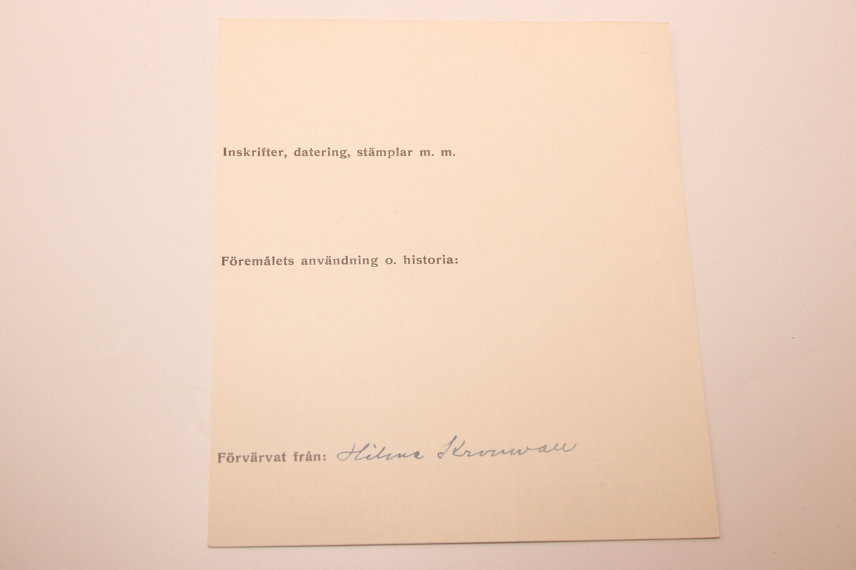 Tobaksdosa i mässing med uppfällbar spegel. Asken öppnas med ett lock i botten. Med gångjärn i ena hörnet där stödet till den uppfällbara spegeln är gängat.  Inskription i botten med bokstäverna ”APL" och siffrorna 1873 efter. Förutom inskriptionen finns inga dekorativa element på föremålet.