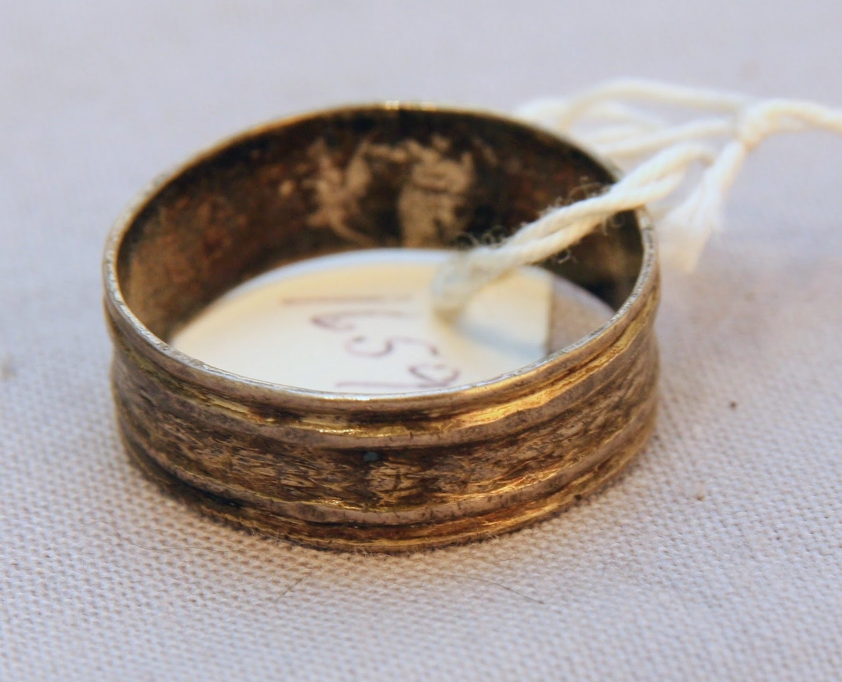 En oval ask av svept spån. Grönmålad, locket har röd kant, i mitten är en enkel ros målad. Äskan innehåller en fingerring, två mindre spännen, öronringar och ett litet hängsmycke i form av ett hjärta.