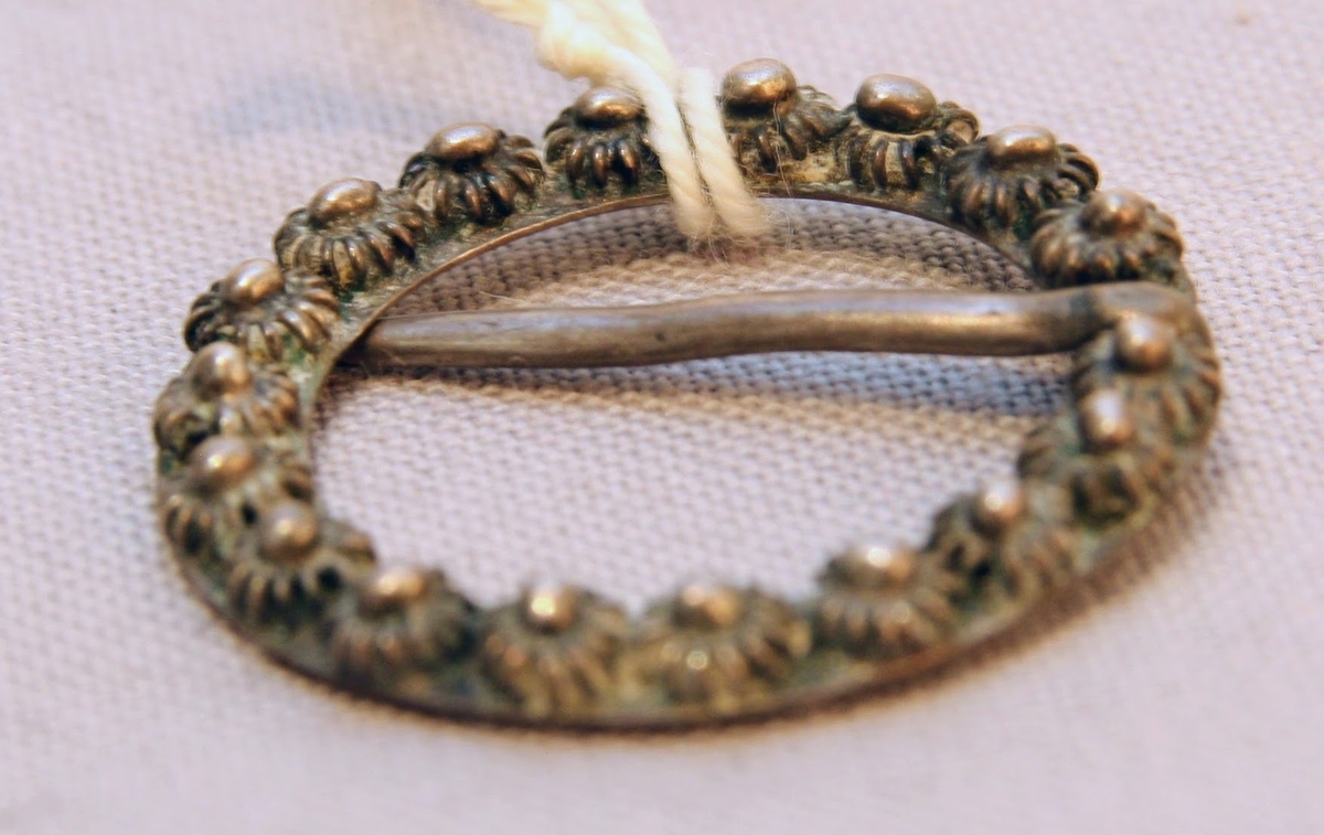 En oval ask av svept spån. Grönmålad, locket har röd kant, i mitten är en enkel ros målad. Äskan innehåller en fingerring, två mindre spännen, öronringar och ett litet hängsmycke i form av ett hjärta.