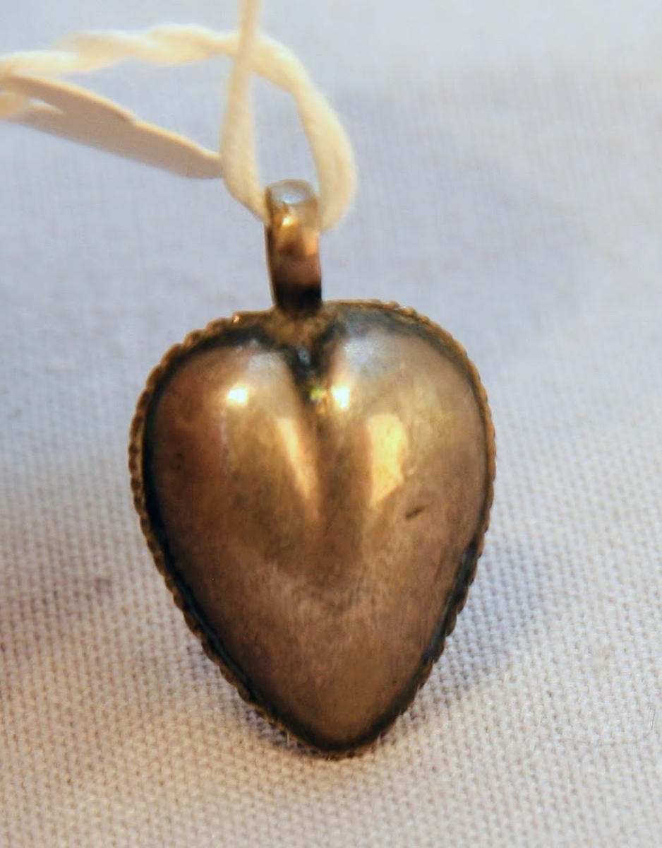 En oval ask av svept spån. Grönmålad, locket har röd kant, i mitten är en enkel ros målad. Äskan innehåller en fingerring, två mindre spännen, öronringar och ett litet hängsmycke i form av ett hjärta.