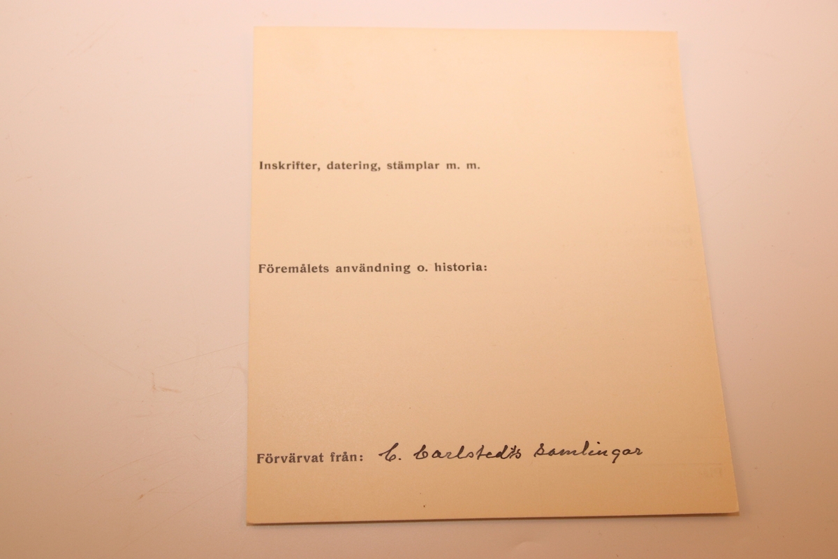 En oval ask av svept spån. Grönmålad, locket har röd kant, i mitten är en enkel ros målad. Äskan innehåller en fingerring, två mindre spännen, öronringar och ett litet hängsmycke i form av ett hjärta.