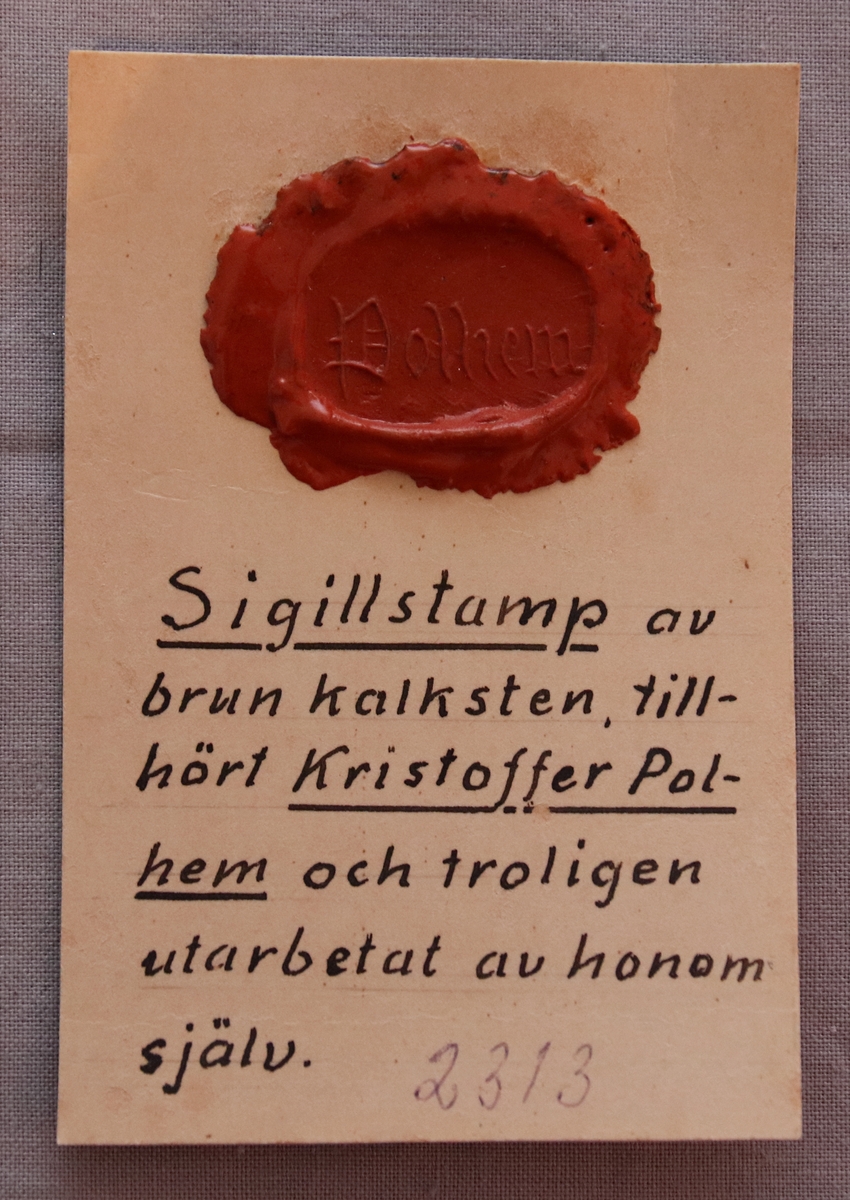 Sigillstamp i brun kalksten. Utformat i arkitektoniska dekorativa element.