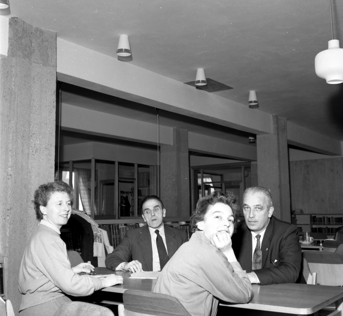 Fra Bokmesse i Elverum 1957
2 menn og 2 kvinner sitter ved bord. i Elverum bibliotek.