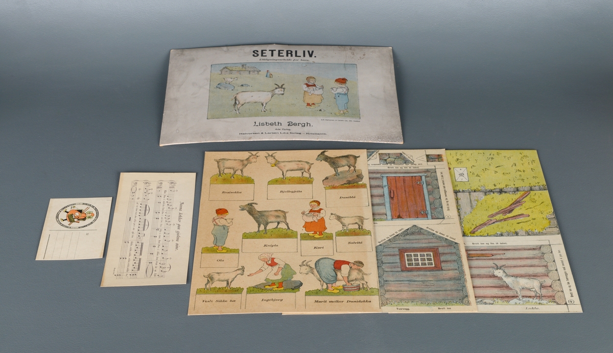 En mappe med utklipningasrbeid for barn. Mappen inneholder tre store ark av tykt papir/tynn kartong med påtrykte figurer som kan klippes ut. På det første arket kan man klippe ut geitene Rosisokka, Bjøllegeita, Duniblå, Knipla, Sølvitå og Vesle Sikke bæ. Man kan også klippe ut Ola som holder en killing, Kari som holder en kattunge og Marit som melker geita Dunidokka. På de to andre arkene kan man klippe ut de ulike delene til seterbygningen og lime dem sammen til et tredimensjonalt hus. Klippe- og limeanvisninger står trykt på arket. På den ene delen til baksiden av huset finenr man også geita Lukla. I mappen ligger det også et lite ark med noter og tekst til "Barna lokker paa gjetene sine". Til sist er det et postkort fra forlaget (ubrukt).