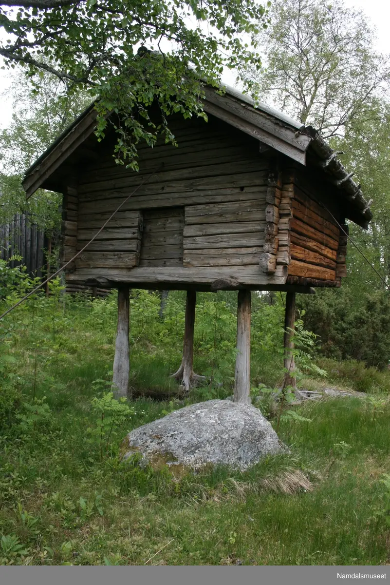 Stabbur som står på fire naturlig vokste rotstokker, ca. 130 cm over bakken.