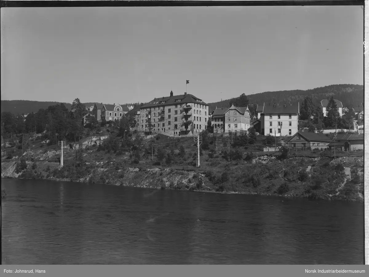 Bymiljø rundt Storgata sett fra elven. Baksiden av A. E. Aasnes gård med blant annet Hotell Norge A/S og Promenadekafeen.