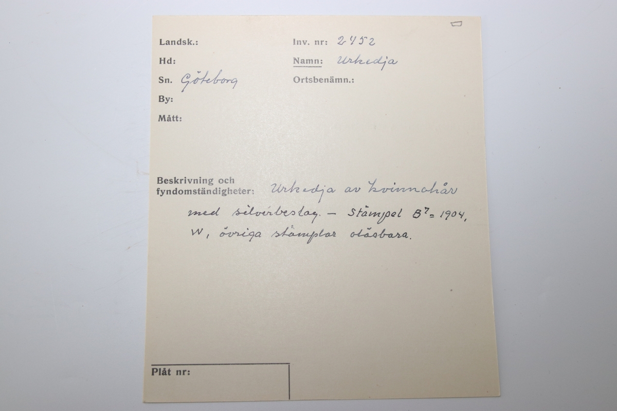 Urkedja av hår med silverbeslag. Med fyrkantig berlock med ingraverade blommor på ena sidan och en sköld på en den andra. Med en platta med ingraverat ”Minne”. - Stämpel B 7 = 1904, W. övriga stämplar oläsbara. -