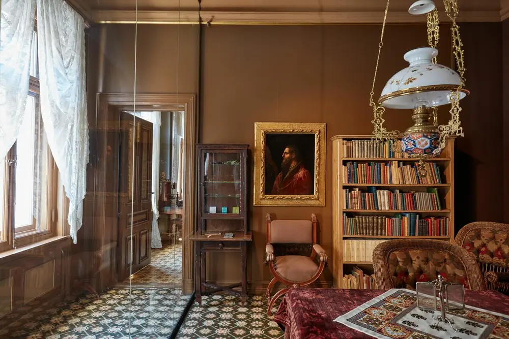 Et sittegruppe med behagelige stoler, bord med rød duk, og en bokhylle med bøker i bakgrunnen. 