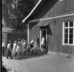 Elever går på led in i skolan när rasten är slut. Bortanför skolan syns björkar.