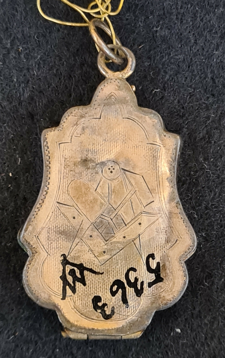 1. Avlång berlock (medaljong) med frimurarsymbol på baksidan. L. 2,9 cm. B. 2 cm.

2. Oval medaljong, troligtvis silver.Röd sten.  L. 2,7 cm  B. 2,4 cm