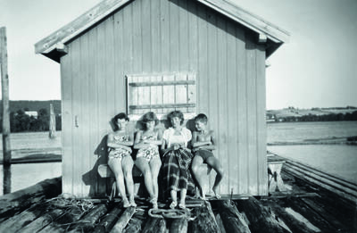 Foto av ungdommer i badedrakter ved hvilebrakke. Eldre foto.