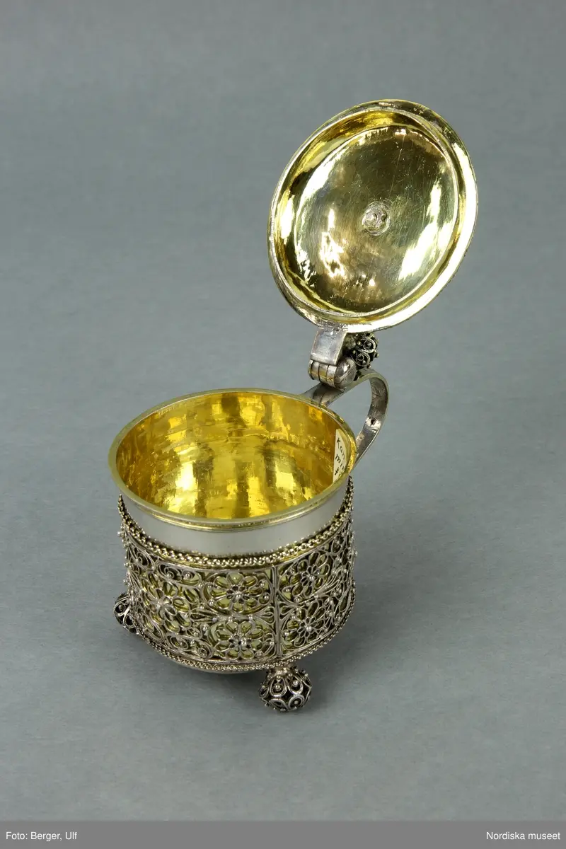 Dryckeskanna i miniatyr, silver, cylinderformad på tre kulfötter, förgylld med filigrandekor, karolinsk barock. stämplad Johan Ståhle, (mästare i Stockholms guldsmedsämbete 1677-1687/1694).
/Ulla-Karin Warberg 2021-11-29