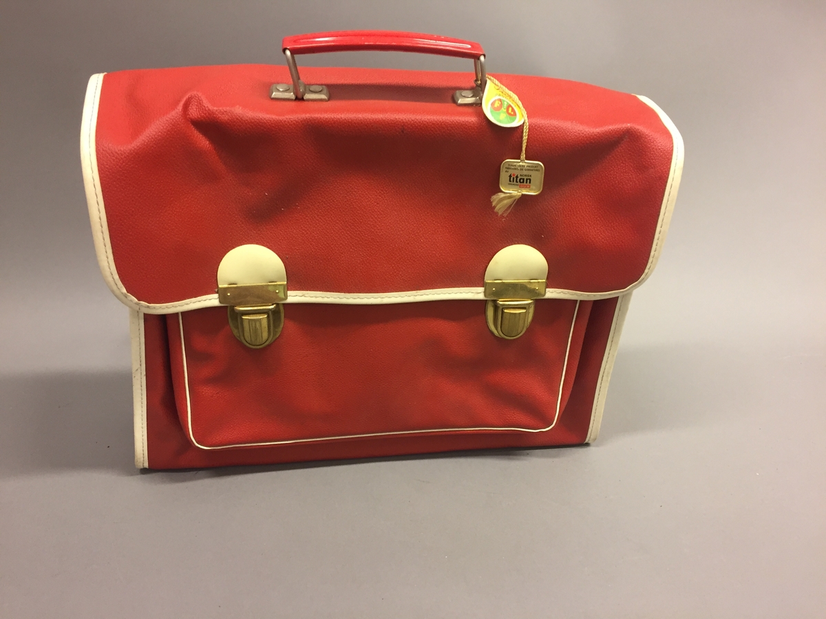 Ransel med to rom. To låsar. Plastlomme til timeplan. Reimane kan festast i sida. Handtak. Merkelappar heng på.