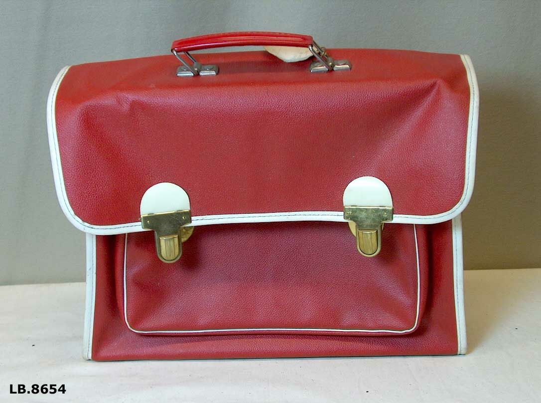 Ransel med to rom. To låsar. Plastlomme til timeplan. Reimane kan festast i sida. Handtak. Merkelappar heng på.