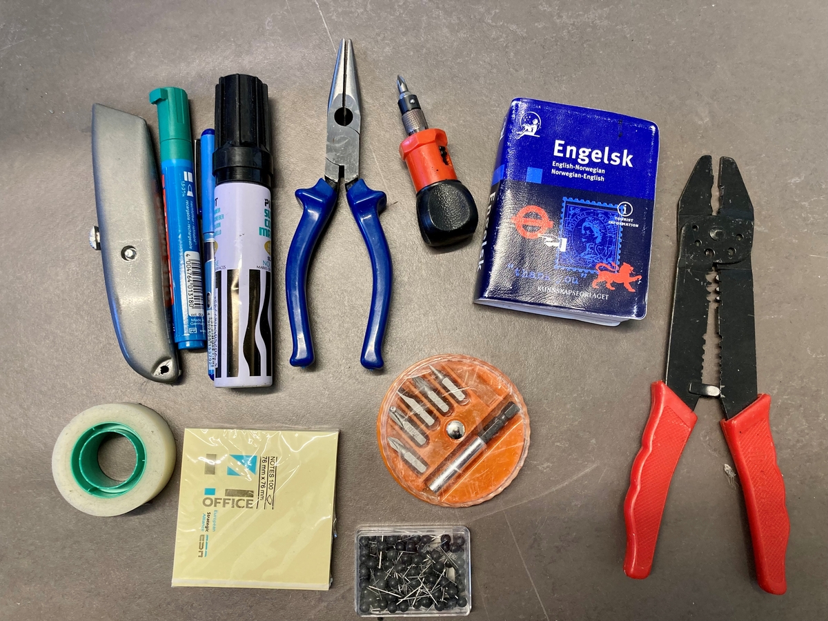 Koffert i metall som inneholder telefon og telefonsentral, opptaksutstyr og flere øretelefoner, lange telefonledninger, samt noe verktøy og kontorrekvisita, som skrujern, tapetkniv, tusjer, skrujern notatpapir, stifter, ekstra batterier mm.