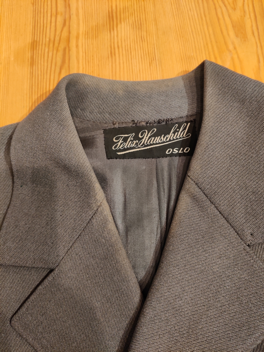 Grågrønn uniform med liggende krave og fire lommer, ridebukse og skilue (Finn Quales modell). Uniformen har bruksmerker, særlig på kraven. Luen er slitt, foret har løsnet. Alle gradstegn og knapper er fjernet fra jakken. God kvalitet på stoffet, muligens offisersuniform. (NB: Fremstår som grå på bildene, men har i virkeligheten en blass militærgrønn farge.)