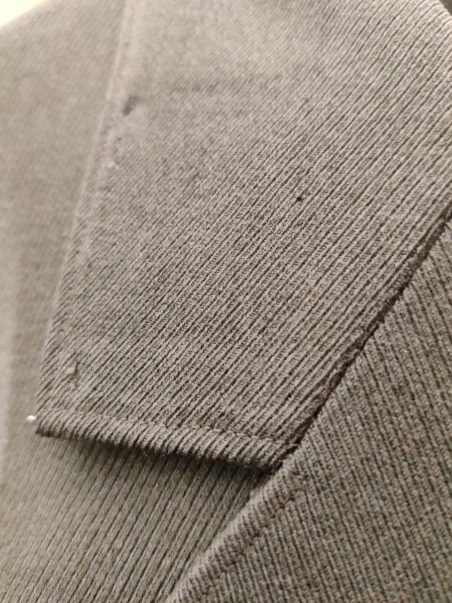 Grågrønn uniform med liggende krave og fire lommer, ridebukse og skilue (Finn Quales modell). Uniformen har bruksmerker, særlig på kraven. Luen er slitt, foret har løsnet. Alle gradstegn og knapper er fjernet fra jakken. God kvalitet på stoffet, muligens offisersuniform. (NB: Fremstår som grå på bildene, men har i virkeligheten en blass militærgrønn farge.)