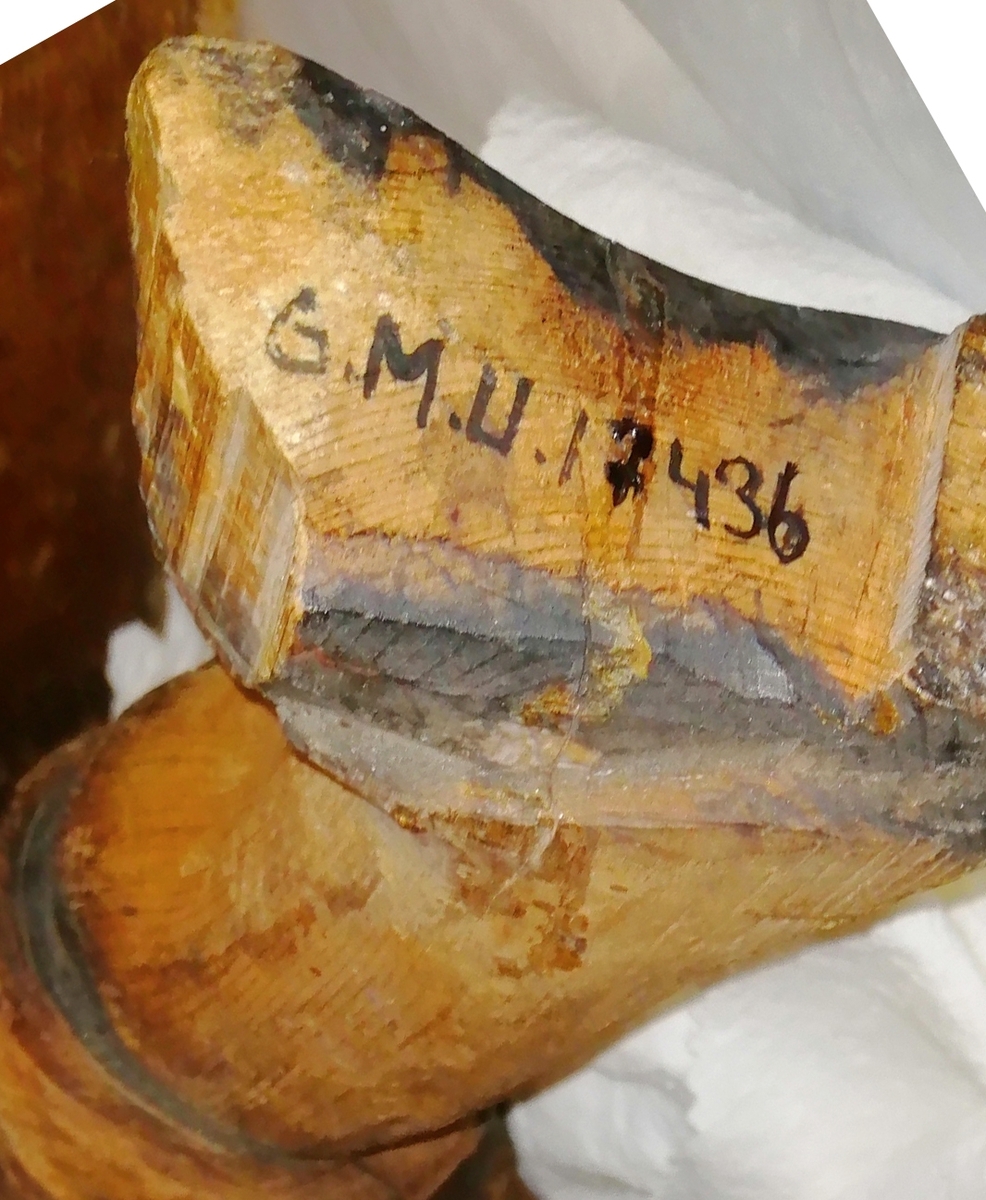 Trägubbe, skulpterad. Löstagbar mage. Invändigt klädd med brev. Trasig.
