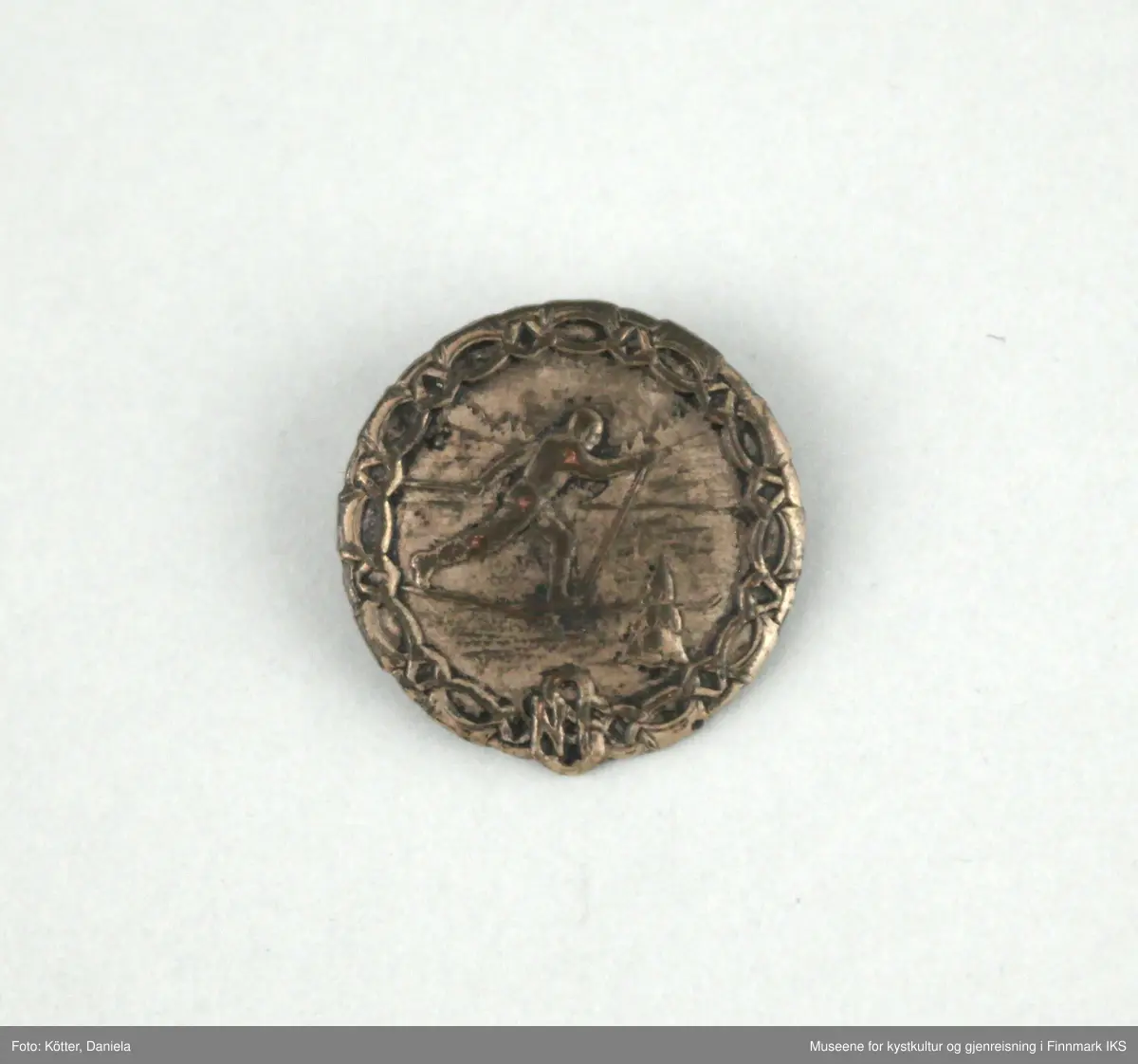 Merket er rund og har et nål festet på baksiden. Det kan være et sølv- eller bronsemerke. Forsiden viser en skiløper i naturen. Kanten er dekorert med et båndornament og nederst i midten er initialene NSF.