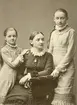 Systrarna Clara, Maria och Anna Jacobsson. Döttrar till handlare Carl Jacob Jacobsson och makan Clara Maria Sandberg. Fototillfället är odaterat men ägde utifrån systrarnas åldrar rum omkring år 1880. Familjen bodde då i vad samtiden kallade Wallenbergska gården invid Nygatan.