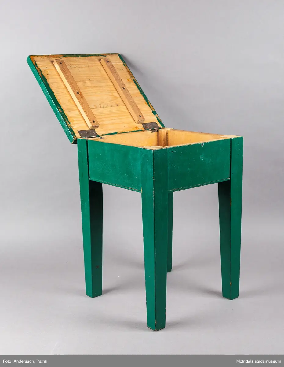 Grön sängpall/sängbord med förvaring. Pallen är 43 centimeter hög och 30 centmeter bred. Den är tillverkad i trä och målad i mörkgrönt. 

Gåva: Föreningen Gåreviks Barnkoloni. Pallen har stått i sovsalen. Varje barn hade en pall vid sin säng, som de kunde förvara sina privata tillhörigheter i.