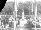 Fotografi i samband med invigningen av Per Brahe-bysten på Gränna torg 1916. En folksamling kring bysten en talarstol till vänster om densamma. En man hög hatt talar.