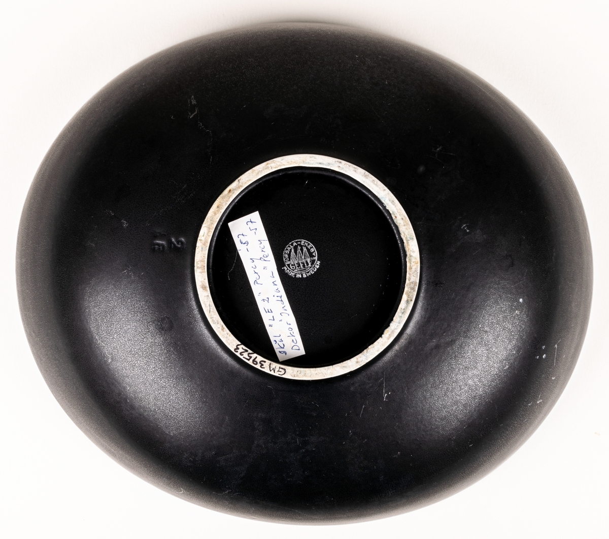 Större oval skål i flintgods med dekor Indiana i modell LE2, forrmgiven av Arthur Percy för Gefle porslin 1957. Insidan har turkos glasyr, utsidan har den matta svarta glasyren Negro. Längs skålens kant på insidan finns upphöjda dekorativa prickar i godset.