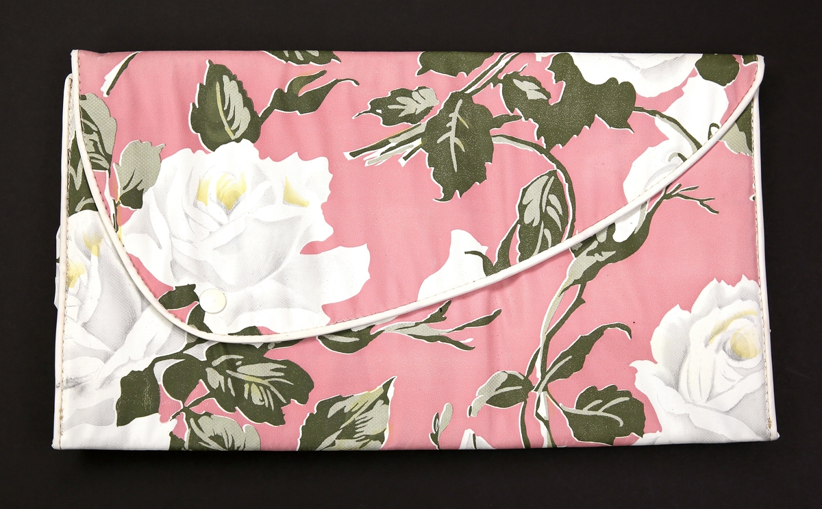 Toalettmappe med blomstermotiv, hvite roser med grønne blader, på rosa bunn.
