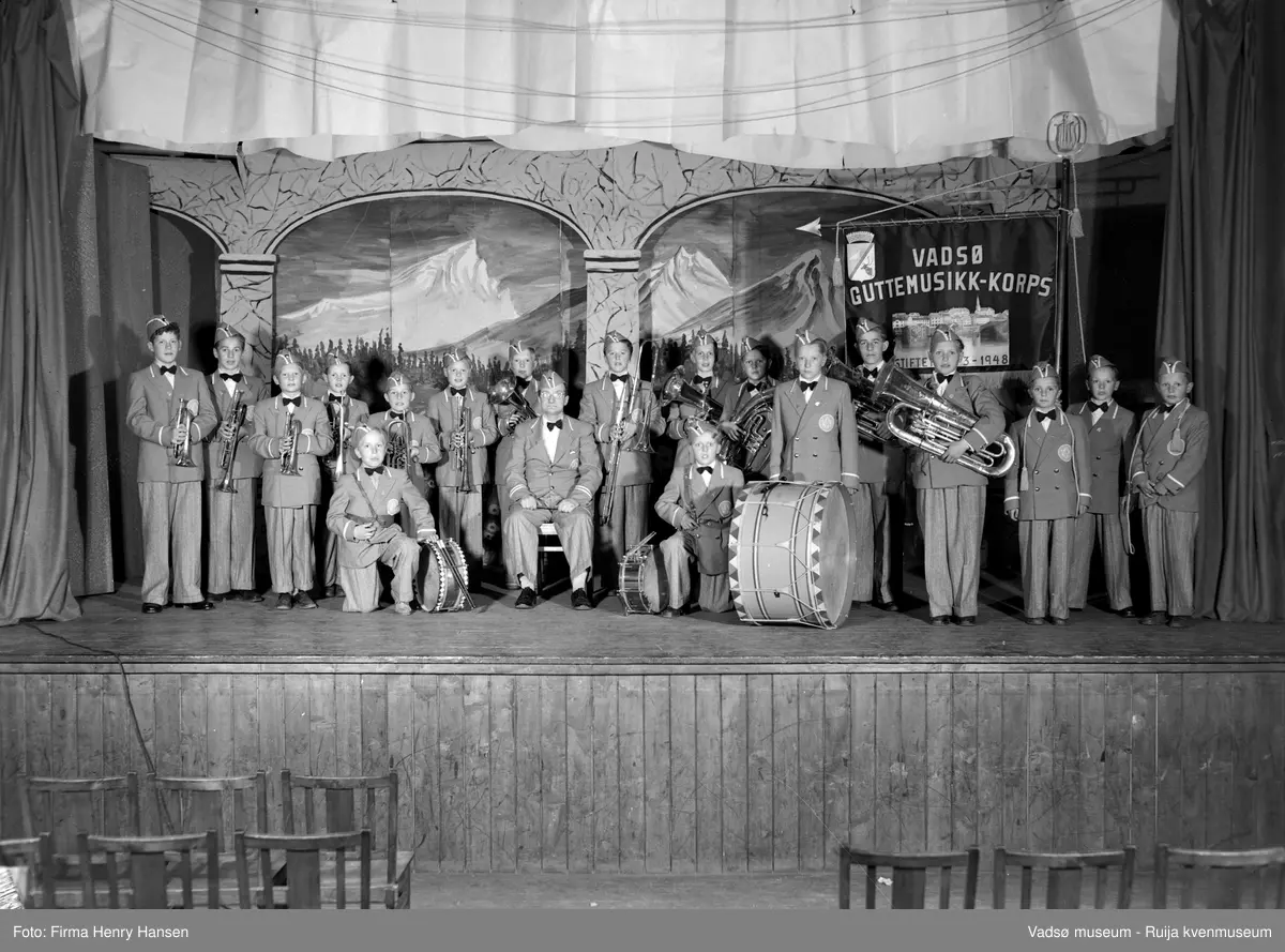 Vadsø guttemusikk-korps på scenen i Vårbrudd. Dirigent Olav L. Holmen sitter i midten foran musikantene. Bildet er tatt ca. 1950-1969. Kilde: Fotosamlinga ved Troms og Finnmark fylkesbibliotek.
Musikanter 1 Albert Moe, 2 Ragnar Wara, 3 Per Norvik, 4 Fredrik Lebesby, 5 Rolf Berg, 6 Terje Waaktor, 7 Terje Joki, 8 Dirigent Olav Holmen, 9 Atle Eimjellen, Ivar Nelsvik, 11 Svein Holsbø, 12 Jarl Methi, 13 Andreas Berg, 14 Harald Sørum, 15 Tor Gundersen, 16 Erling Henriksen, 17 Kjell Gundersen, 18 Frits Pettersen, 19 Tor Rushfeldt  ( se nummer markert på bilde 2).