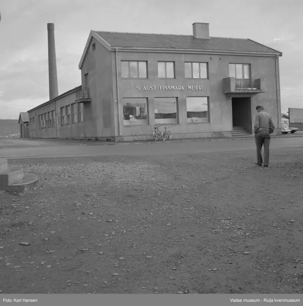 A/L Aust-Finnmark Meieri, 1962 i Vadsø. Bildet er tatt mot øst.  
Arbeidet med å få meieri til Vadsø ble påbegynt før krigen.  Ønsket var å få et meieri som kunne dekke Nord-Varanger-Tanadistriktet.  Andelslaget A/L Aust-Finnmark Meieri ble stiftet 28.juni 1947 i Nyborg.  
Aust- Finnmark Meieri ble oppført i Tollbugata i 1949; arkitekt Monrad Heggen m hovedentreprenør Brdr. Aronsen.
Oppstart skulle finne sted ca 1. oktober 1949, og i mai ble det ansatt en meieriarbeider; Richard Korbi fra Vadsø.
Kilde: "A.L Aust-Finnmark Meieri 25 års jubileum 1949-1974; styreformann Ivar Johnsen, Tana mai 1974"