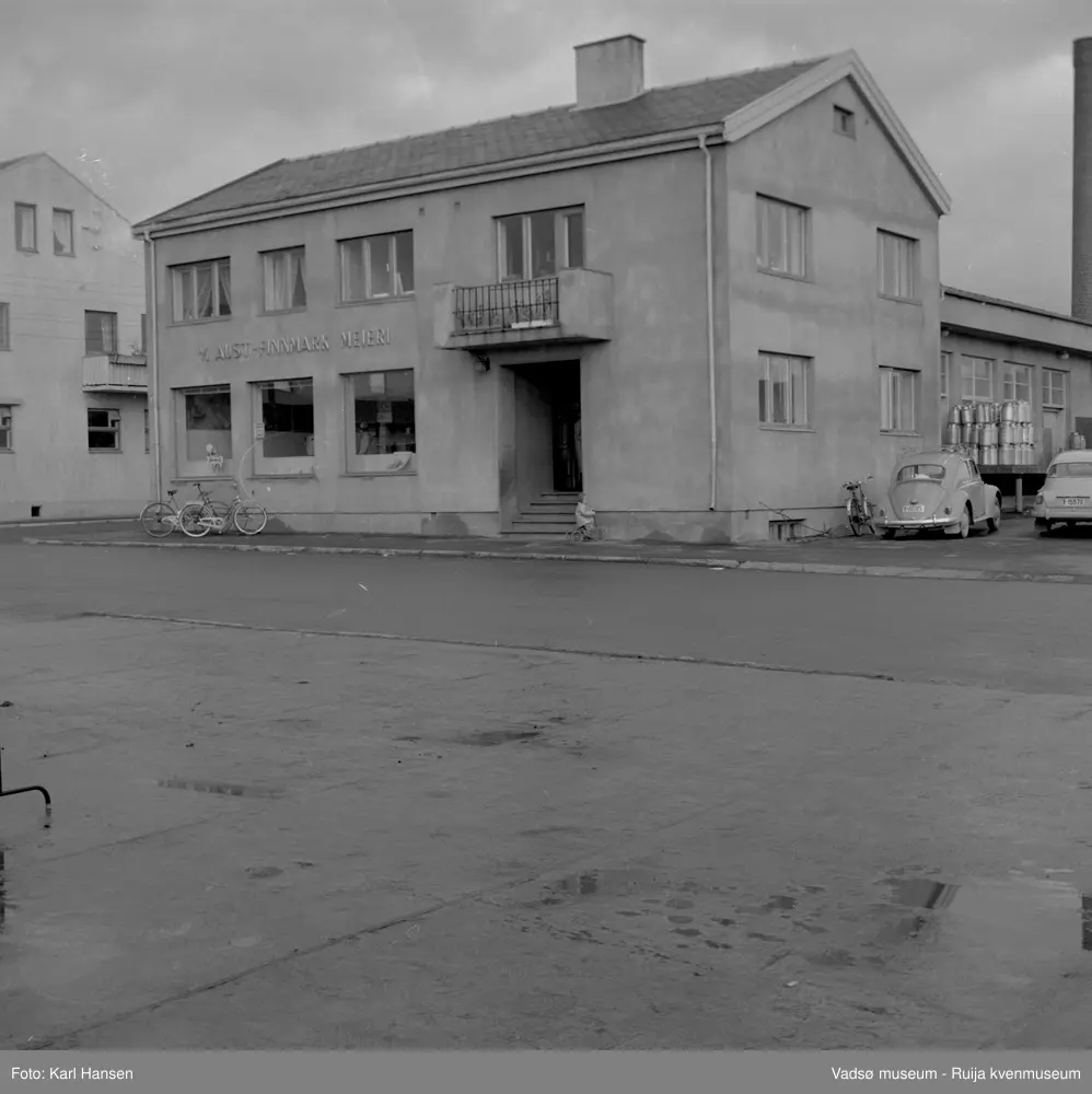 A/L Aust-Finnmark Meieri, 1962 i Vadsø. Bildet er tatt mot øst. Til venstre ser vi deler av H.F. Esbensens forretningsbygg. 
Arbeidet med å få meieri til Vadsø ble påbegynt før krigen.  Ønsket var å få et meieri som kunne dekke Nord-Varanger-Tanadistriktet.  Andelslaget A/L Aust-Finnmark Meieri ble stiftet 28.juni 1947 i Nyborg.  
Aust- Finnmark Meieri ble oppført i Tollbugata i 1949; arkitekt Monrad Heggen m hovedentreprenør Brdr. Aronsen.
Oppstart skulle finne sted ca 1. oktober 1949, og i mai ble det ansatt en meieriarbeider; Richard Korbi fra Vadsø.
Kilde: "A.L Aust-Finnmark Meieri 25 års jubileum 1949-1974; styreformann Ivar Johnsen, Tana mai 1974"