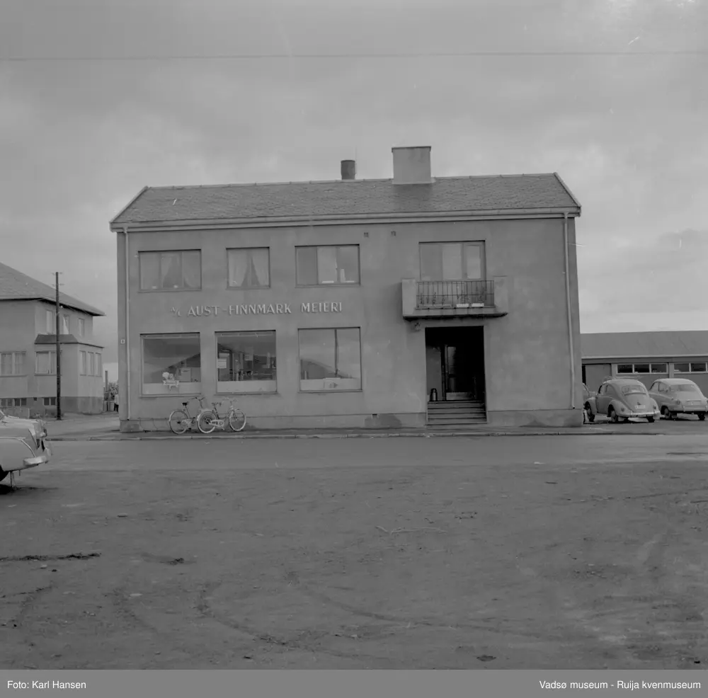 A/L Aust-Finnmark Meieri, 1962 i Vadsø. Bildet er tatt mot øst med fasaden og meieriets inngangsparti.. Til venstre i bildet W.A. Andersensgate og hjørnet av Telegrafbygget.
Arbeidet med å få meieri til Vadsø ble påbegynt før krigen.  Ønsket var å få et meieri som kunne dekke Nord-Varanger-Tanadistriktet.  Andelslaget A/L Aust-Finnmark Meieri ble stiftet 28.juni 1947 i Nyborg.  
Aust- Finnmark Meieri ble oppført i Tollbugata i 1949; arkitekt Monrad Heggen m hovedentreprenør Brdr. Aronsen.
Oppstart skulle finne sted ca 1. oktober 1949, og i mai ble det ansatt en meieriarbeider; Richard Korbi fra Vadsø.
Kilde: "A.L Aust-Finnmark Meieri 25 års jubileum 1949-1974; styreformann Ivar Johnsen, Tana mai 1974"