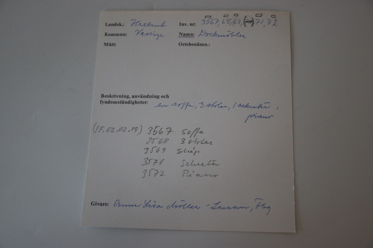 Piano i miniatyr till dockskåp från mitten av 1800-talet. I mörkbrunt målat trä med tryckt dekor i guldig färg på ovansidan och framsidan av pianots ovanstycke och främre nedanstycke. Dekoren föreställer bland annat rocailler, paneler och bårdar i sirlig och asymeterisk stil. Det finns en guldig bård med blomformade maskaroner framtill ovanför tangenterna. Vita fält längst upp och längst ned på främre ovanstycket och nedanstycket (ovanför den tryckta dekoren). Med 15 tangenter (en saknas).