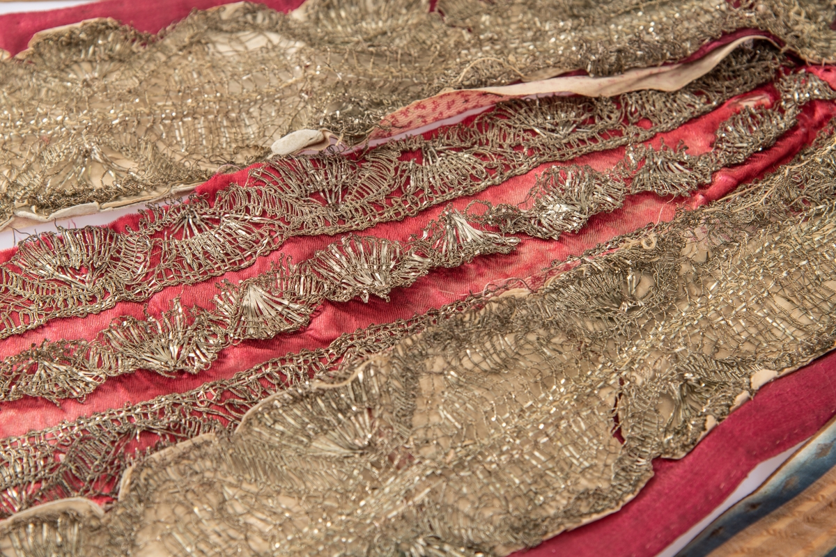 Brudekrone i metall med fem spir. Krona er pyntet med metallheng og glassperler. Det er påsydd valk nederst, med brodert bånd og metallknipling rundt valken.

Bak på det broderte båndet rundt valken, er det festet bånd. På midten er det et bredt bånd i rødt med metallkniplinger, med brede bånd med lys bunn og med en rød kant vendt ut fra den røde midtbåndet. Metallkniplinger er festet til de tre brede båndene. Deretter fire smalere bånd på hver side av de brede båndene. Disse er festet samlet med en liten sløyfe på det bredeste der det er festet på valken. 

En plastkam er påsydd valken sammen med to hvite, nyere bånd. Antagelig gjort i nyere tid for å feste krona og knyte under haka.