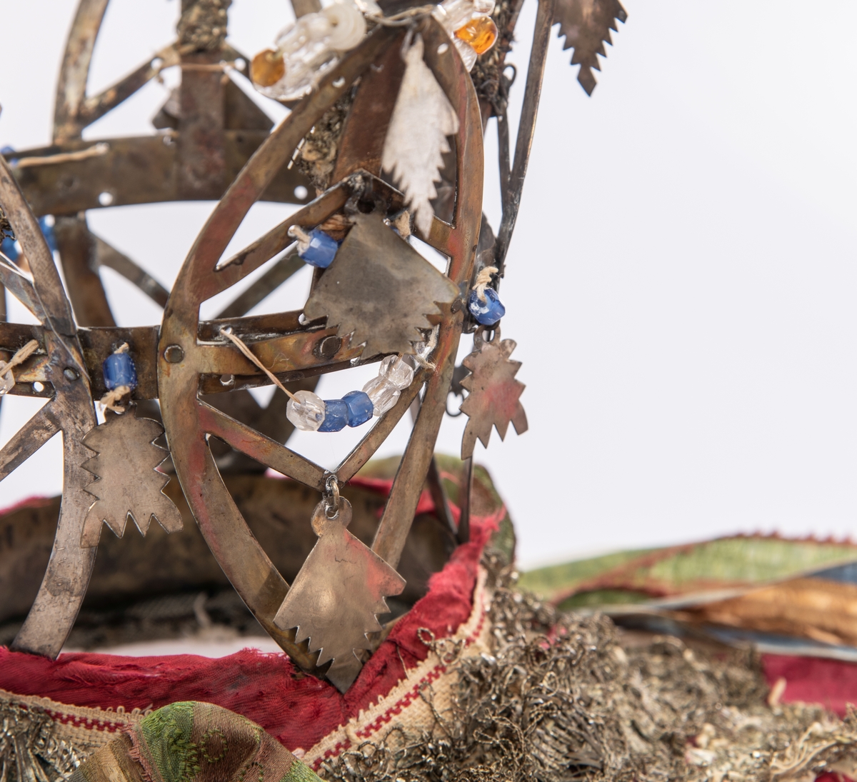 Brudekrone i metall med fem spir. Krona er pyntet med metallheng og glassperler. Det er påsydd valk nederst, med brodert bånd og metallknipling rundt valken.

Bak på det broderte båndet rundt valken, er det festet bånd. På midten er det et bredt bånd i rødt med metallkniplinger, med brede bånd med lys bunn og med en rød kant vendt ut fra den røde midtbåndet. Metallkniplinger er festet til de tre brede båndene. Deretter fire smalere bånd på hver side av de brede båndene. Disse er festet samlet med en liten sløyfe på det bredeste der det er festet på valken. 

En plastkam er påsydd valken sammen med to hvite, nyere bånd. Antagelig gjort i nyere tid for å feste krona og knyte under haka.
