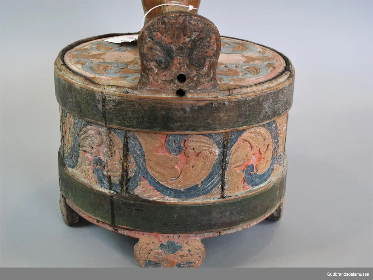 Grøtambar med to ørestaver, lokk med håndtak og to gjorder rundt korpus. Lokket blir festet til ørestavene med tapp i den ene enden av håndtaket og en pinne gjennom et hull i den andre enden. Håndtaket er festet til lokket i en fals. Korpus hviler på tre staver som har utskårne føtter.
Dekor. Malt skurd i rødt gult og blått, fargetrenden seint på 1700-tallet, tidlig 1800-tallet. All maling er svært falmet og slitt. Skurden på korpus og lokk har tydelige stengler med mye bladverk. Lokket har stengler i rocaille med c-former, et stilelement fra rokokkoen.