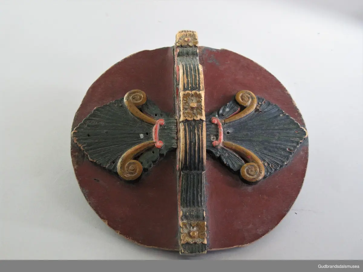 Grøtambar med to ørestaver, lokk med håndtak og to gjorder rundt korpus. Lokket blir festet til ørestavene med tapp i den ene enden av håndtaket og en pinne gjennom et hull i den andre enden. Håndtaket er festet til lokket i en fals. Korpus hviler på tre av stavene som har utskårne føtter.
Lokk og ører har malt skurddekor. Lokket har skurd med palmettmotiv i nyklassisistisk stil. Korpus er rosemalt med en enkel, tydelig ranke med lite utviklet bladverk. Fargebruken på både skurd og rosemalingen er holdt i det seine 1700-tallets, det tidlige 1800-tallets mørkere grønne og gule farger.
I ambarbunnet er det innrisset en seksbladrose.