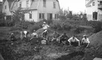 Ett gäng pojkar och män letar efter fynd i uppgrävda massor från vallgravarna vid Rumlaborg i Huskvarna 1932. Vallgravarna hade grävts ur vintern 1931 och sommaren 1932 grävdes ytterligare i den innersta vallgraven. Massorna kördes i skottkärror till en plats vid sidan av borgen där de gicks igenom. Stående är fil. stud Anders Lindahl och strax till höger om honom, tittandes in i kameran är fil. stud. Walter Fredriksson.