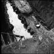 Delar av schakt H nedanför östra delen av borgkullen vid Rumlaborg i Huskvarna. Fotot är taget i samband med arkeologiska undersökningar sommaren 1937. Huskvarna hembygdsförening bedrev undersökningar vid borgen vid flera tillfällen mellan 1931 och 1942 och på bilden syns rester efter en träpalissad som genom undersökningarna kunde urskiljas på flera platser längs med borgkullens kant.