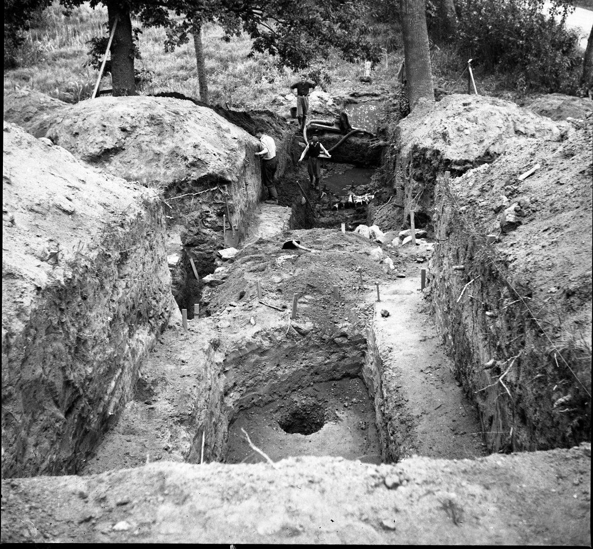 Schakt D genom den södra delen av borgkullen vid Rumlaborg i Huskvarna sommaren 1938. I nedre delen av schaktet kan en rad med pålar skymtas och bakom den en pump som användes för att få undan inträngande vatten från schaktet.