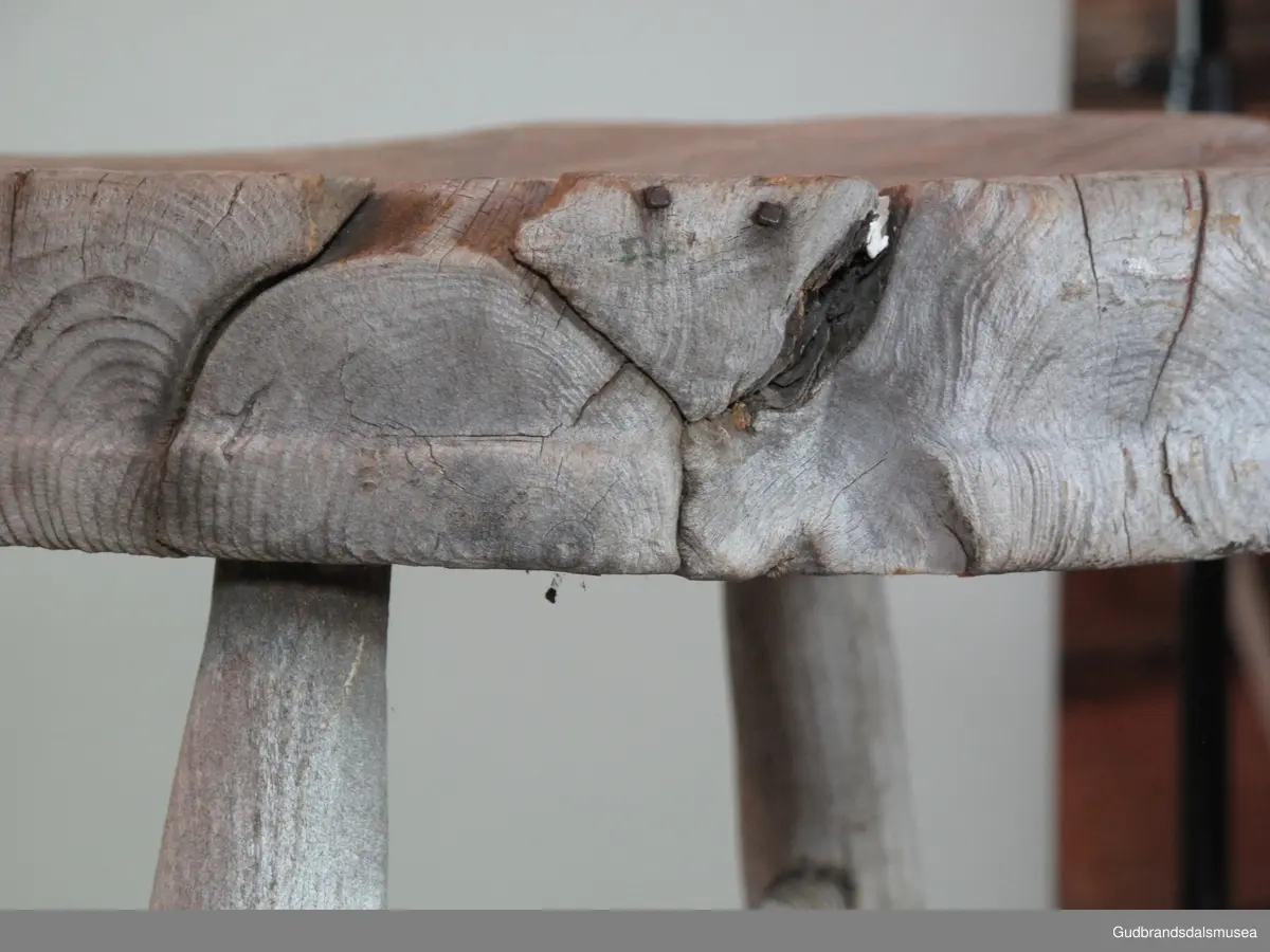 Firbeinet krakk. Beinene er dreid, tappet i stolsetet og i tillegg holdt på plass av to sposser i kors, festet til hverandre med en skrue. Sprossene er festet til beinene med dreid skugang i endene. Treet i setet har sprekker pga. inntørking. Løse trestykker som følge av inntørkingen har blitt spikret fast.