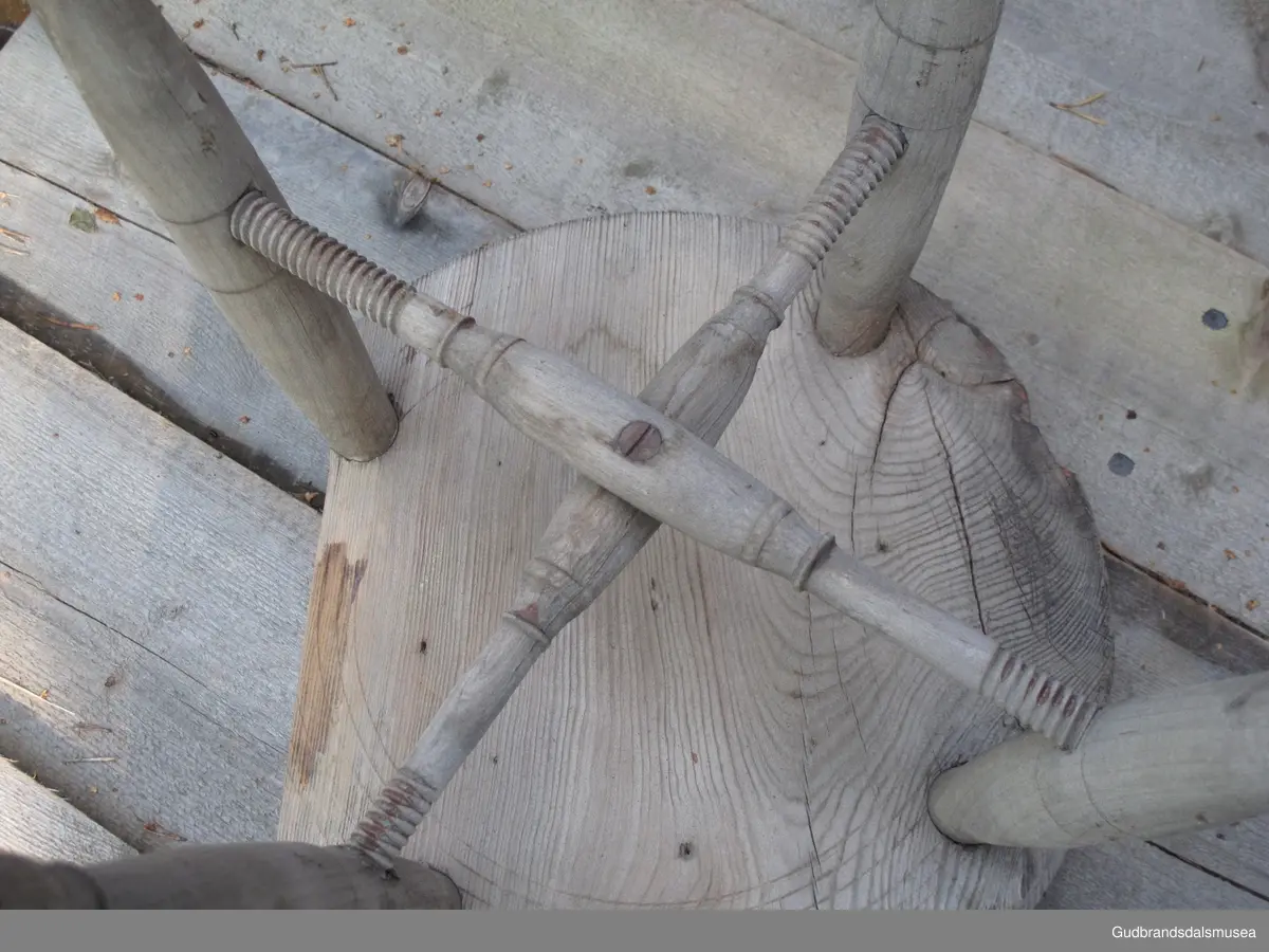 Firbeinet krakk. Beinene er dreid, tappet i stolsetet og i tillegg holdt på plass av to sposser i kors, festet til hverandre med en skrue. Sprossene er festet til beinene med dreid skugang i endene. Treet i setet har sprekker pga. inntørking. Løse trestykker som følge av inntørkingen har blitt spikret fast.