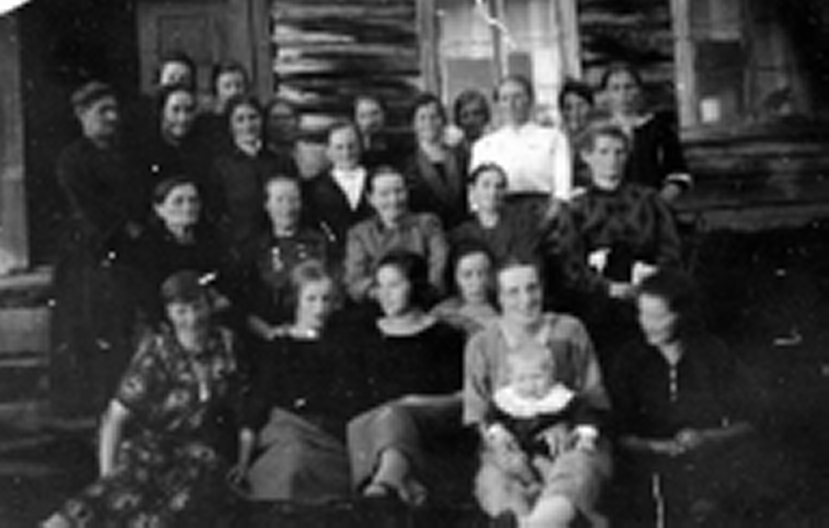 Gruppe med kvinner og et barn fotografert utenfor stua. Sannsynlig gården Helberg i Maukdalen i 1925.