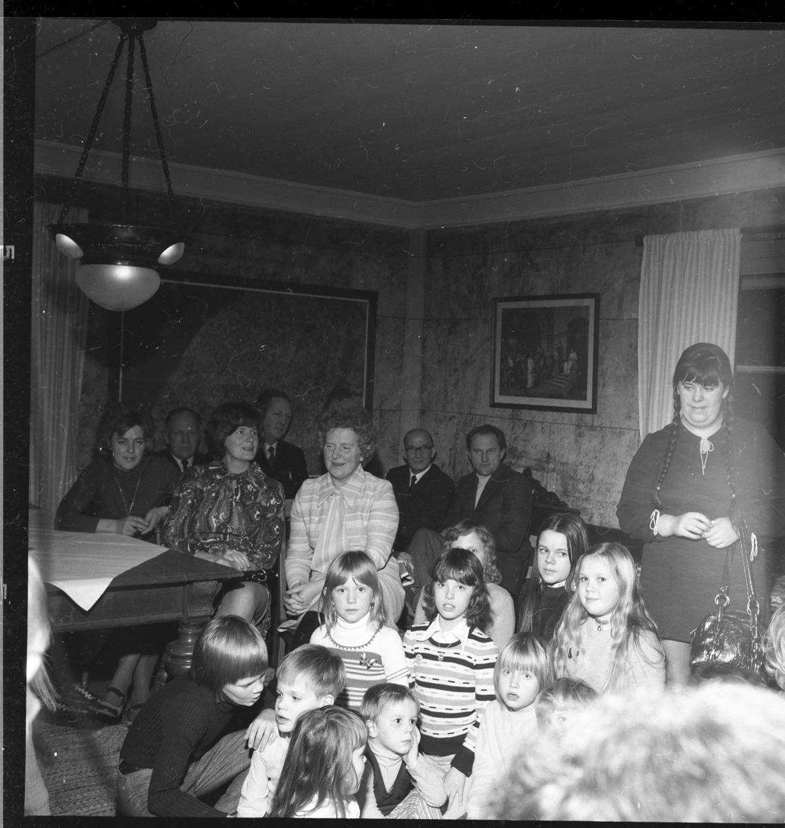 Vuxna och barn i en stuga. Ölmstad hembygdsförenings julfest.