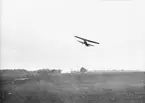 Flygplan S 6 , Fokker C.V flyger över flygfältet på Malmen. De så kallade Röda och Gula förråden i bakgrunden. Omkring 1927-1935.