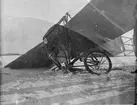 Ett flygplan Thulin A har havererat vid landning. Landningsstället har vikt sig. Vintertid, omkring 1915.