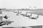 En division av flygplan A 32A Lansen uppställda på flygfältet på F6 i Karlsborg, omkring 1962-1965. Flygplan Tp 55 är på besök, I bakgrunden syns två flygplan A 32 som just har startat.