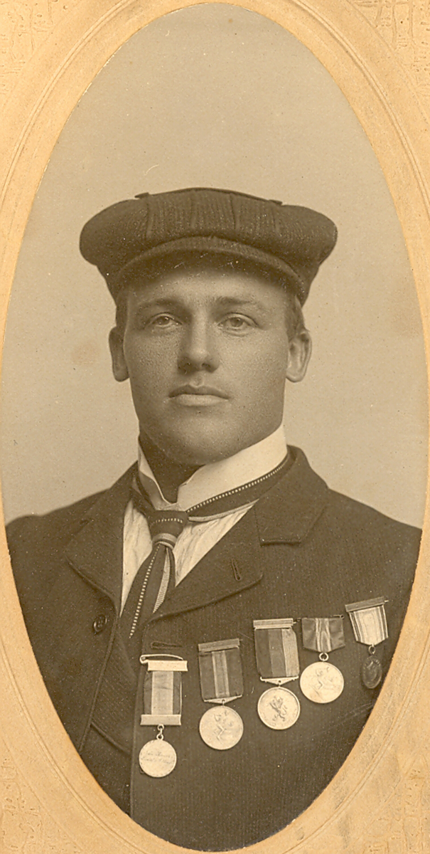 Ovalt brystbilde av Knut G. Helland i Amerika i 1906. Han har fem skimedaljer på brystet.