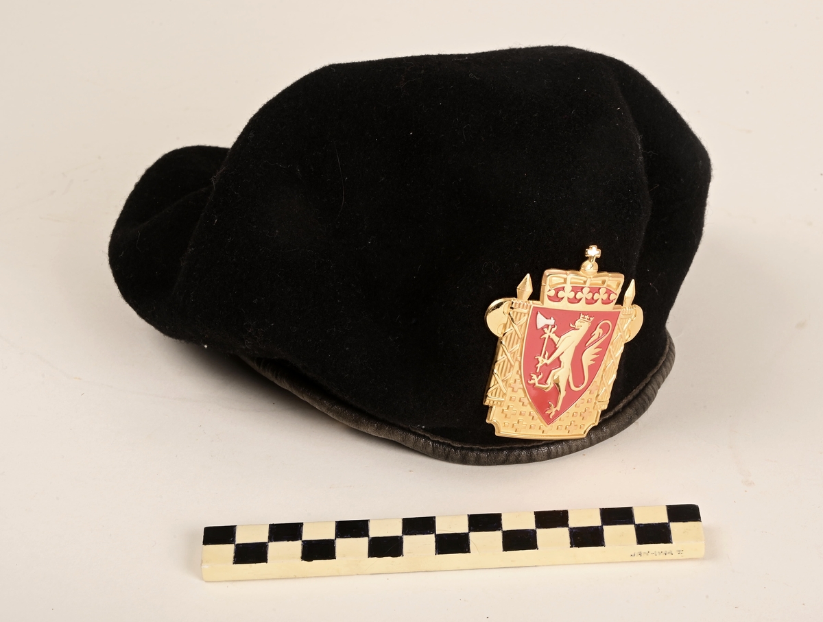 Uniformslue med emblem. 
Luen og emblemet inngår i politiets uniformsportefølge. Likevel hører ikke denne luen og dette uniformsmerket sammen i følge politiets uniformsreglement.